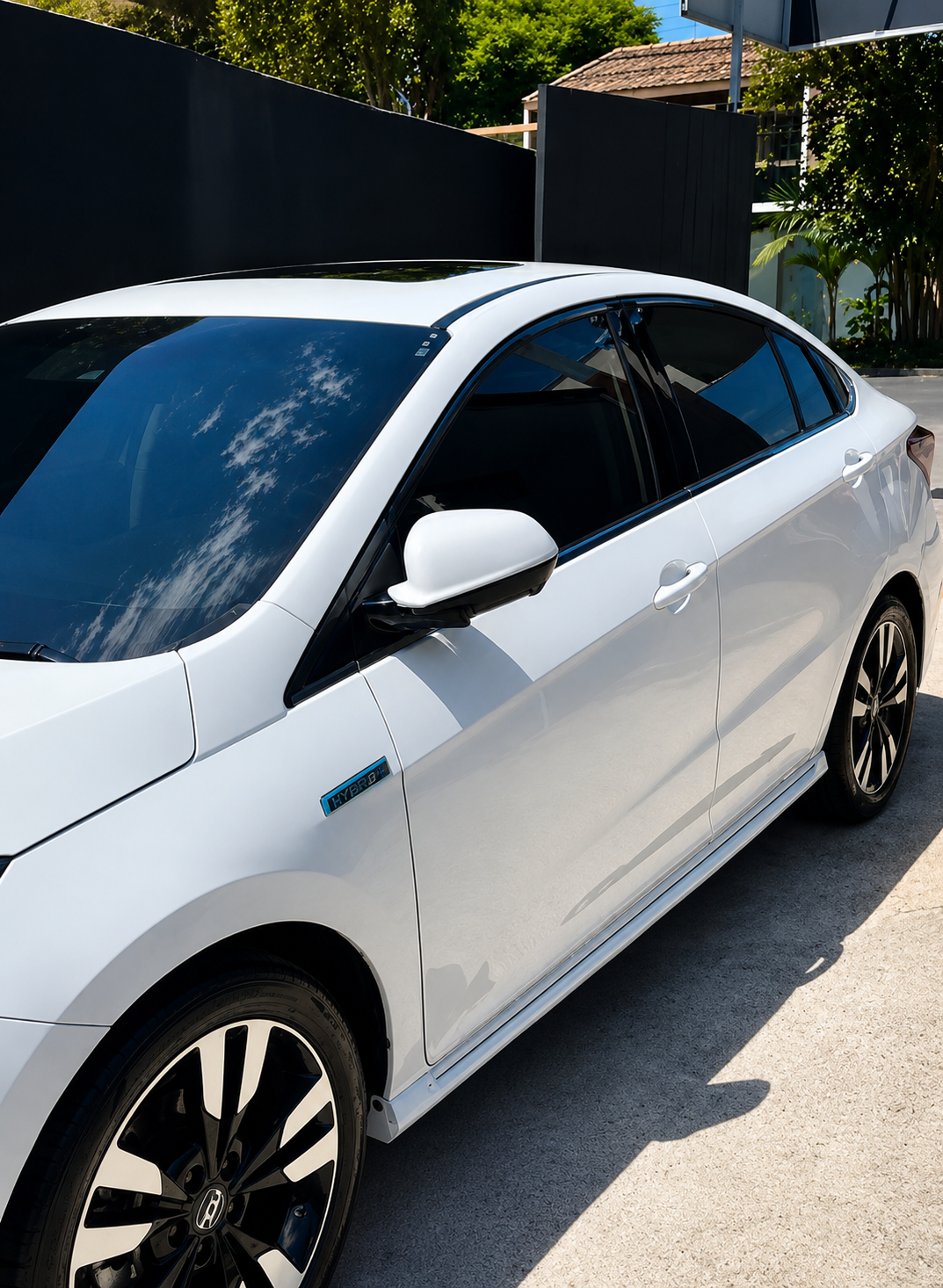 Detalhe lateral de Honda branco com película automotiva e reflexo elegante nos vidros.