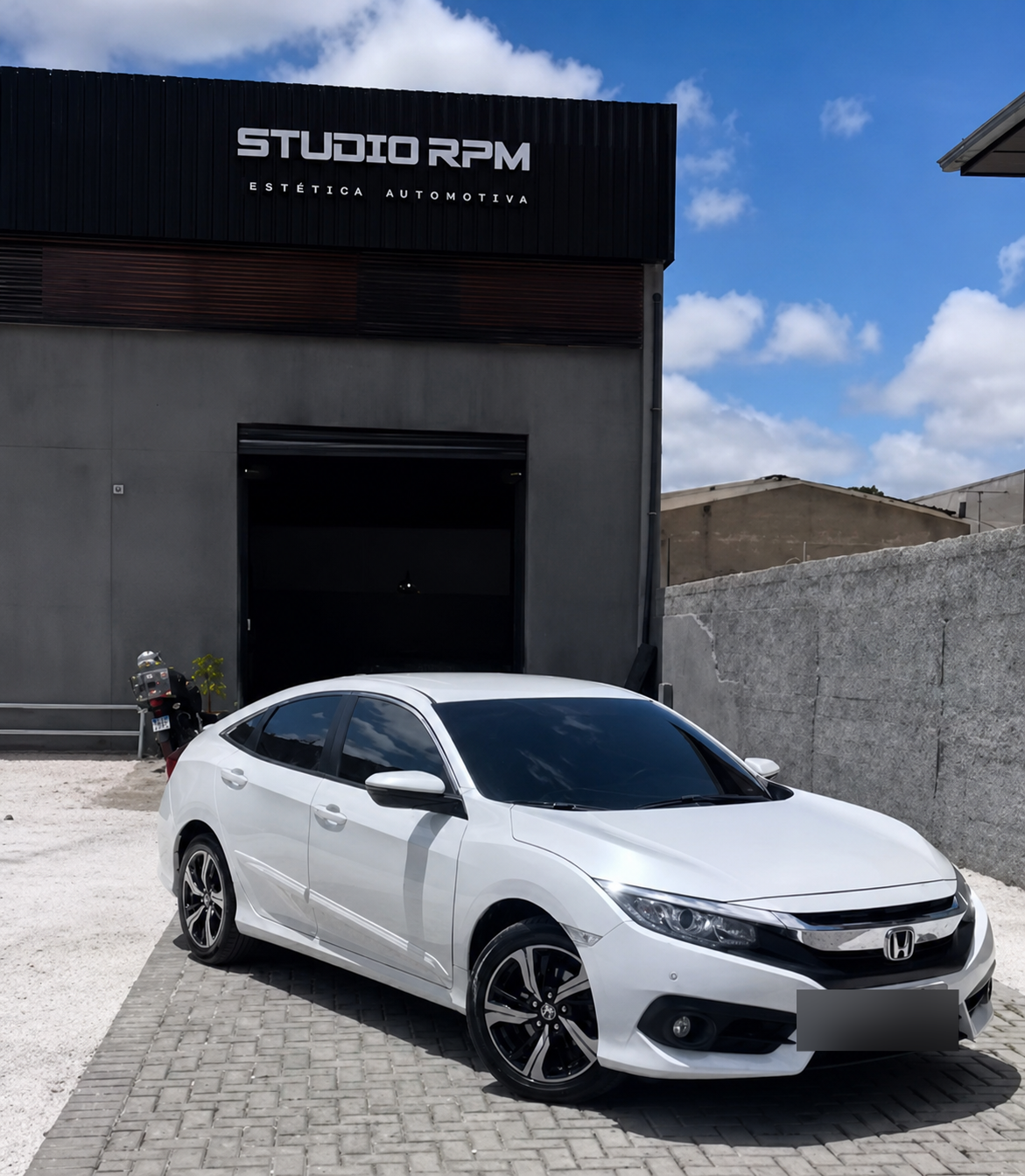 Honda Civic branco com película automotiva Studio RPM em frente à fachada da loja.